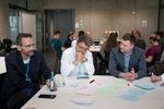 Auch in diesem Jahr waren wieder zahlreiche Workshops  auf der authenticon. So konnten Konferenzteilnehmende nicht nur zuhören, sondern auch selbst aktiv werden. Im Bild sieht man zwei Tische an den jeweils eine Gruppe an Menschen drum herum sitzt und einen regen Austausch haben, während Dinge auf verschiedene Papierausschnitte schreiben um die Ergebnisse später an Magnettafeln anzuheften und vorzustellen.